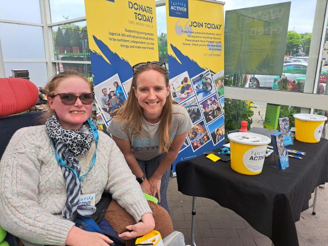 Two volunteers with buckets at a stall.
